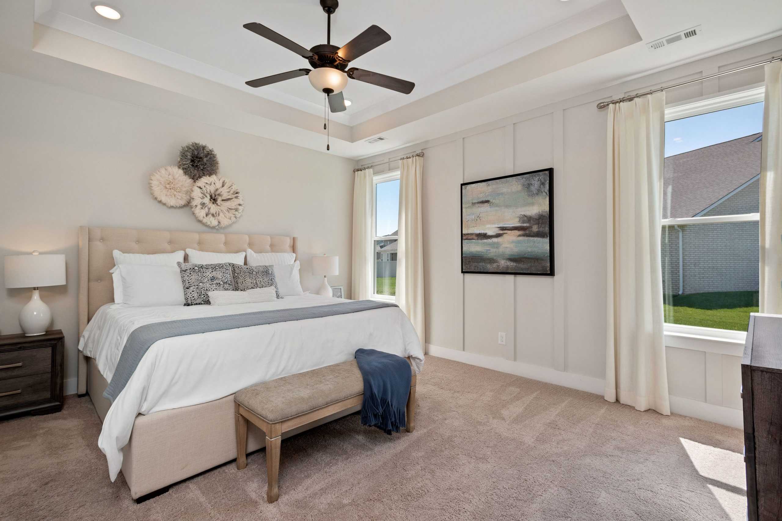 Spacious master bedroom at Rivers Edge in Murfreesboro TN with king bed, beige shiplap walls, ceiling fan, and sheer-curtained windows