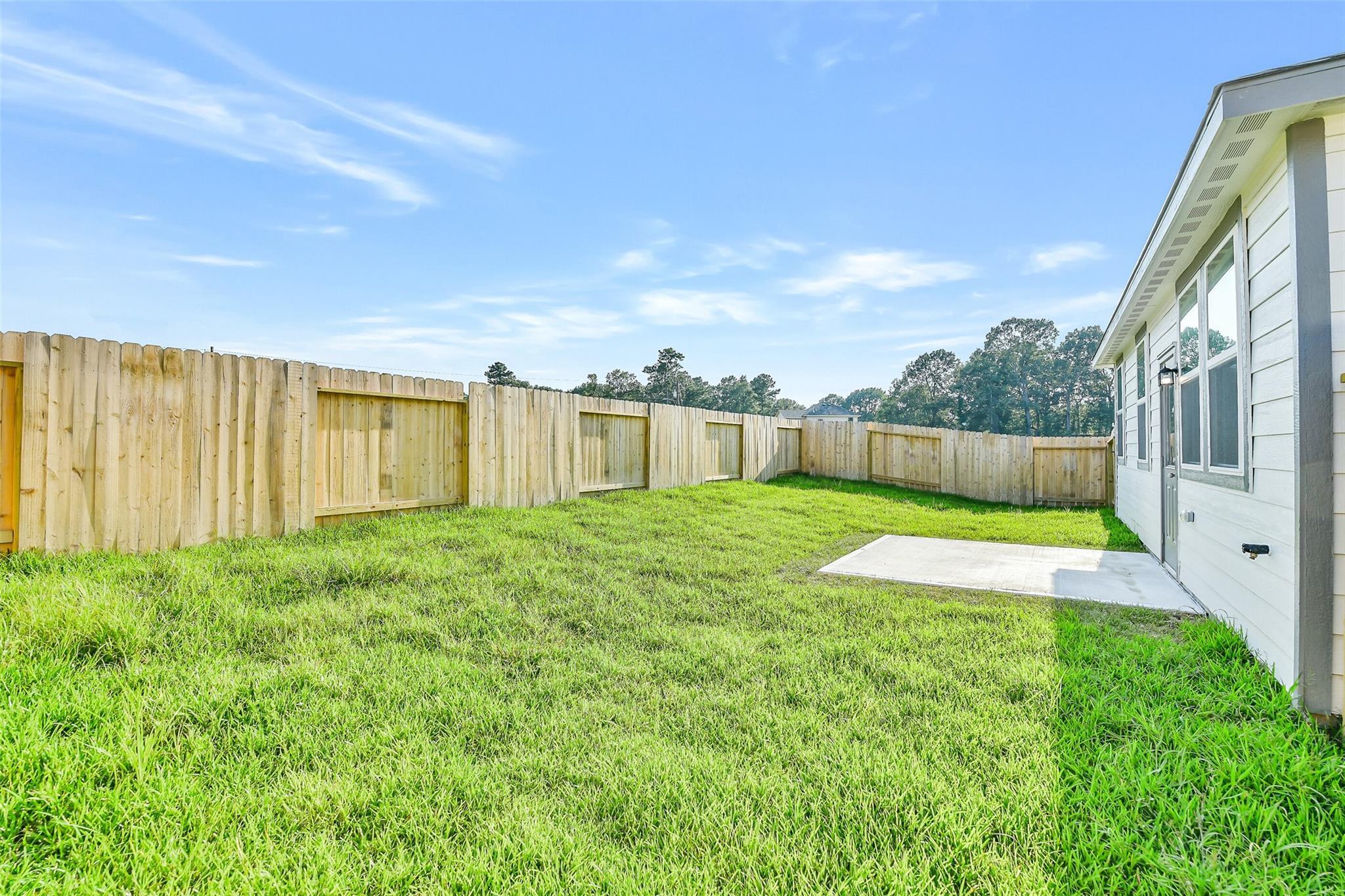 Private fenced backyard with lush green lawn and concrete patio in Davidson Homes The Colorado F, Liberty Estates, Cleveland, Texas