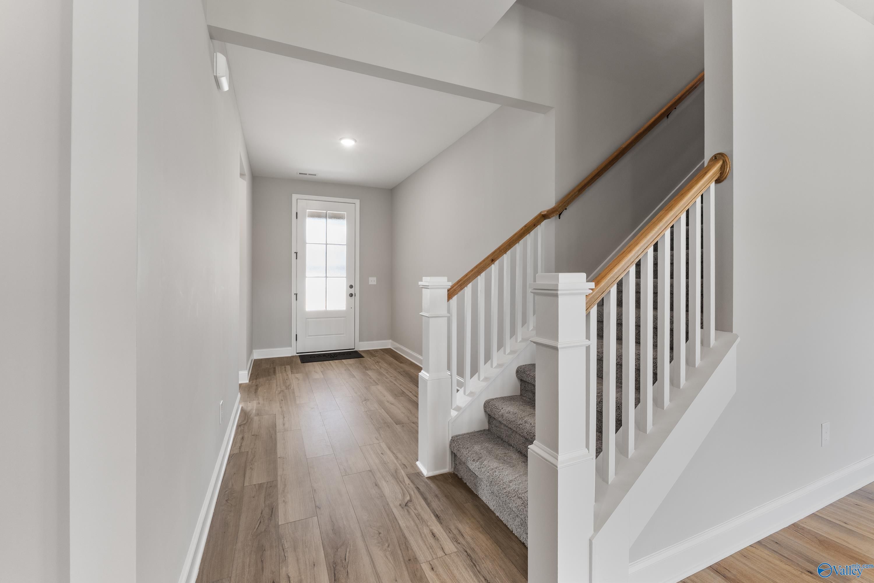 Welcoming entry foyer with oak staircase, hardwood floors, and white door in Davidson Homes Montgomery B With Bonus, Toney, AL