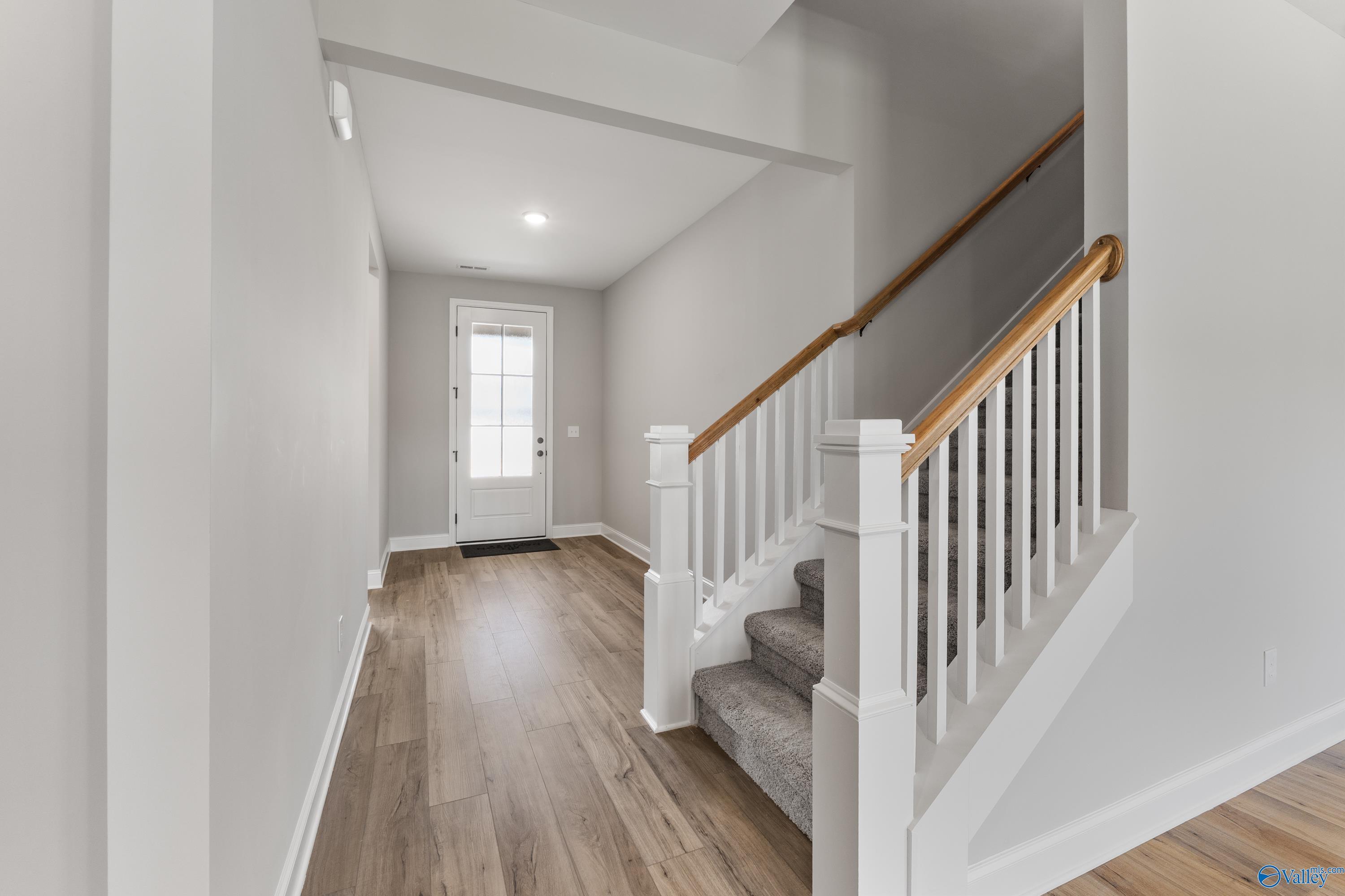 Welcoming entry foyer with oak staircase, hardwood floors, and white door in Davidson Homes Montgomery B With Bonus, Toney, AL