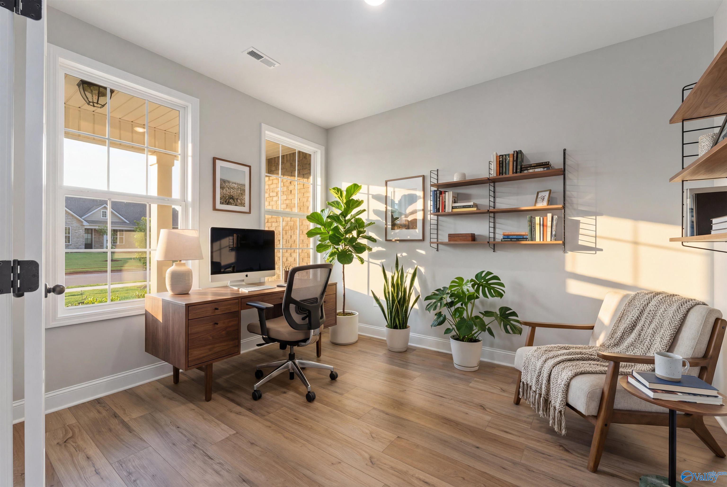 Cozy home office with wooden desk, potted plants, bookshelves, and armchair in Davidson Homes The Rockford, Toney AL