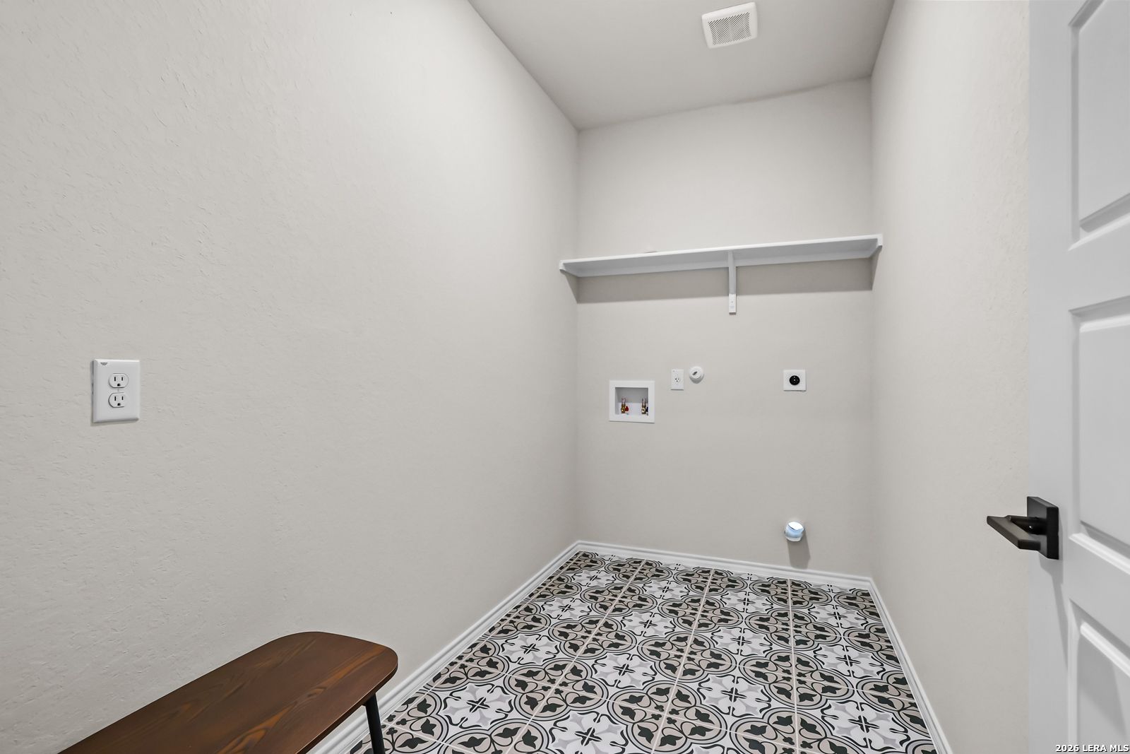 Laundry room with patterned tile flooring and storage shelving in The Douglas C floor plan at Hannah Heights, Seguin, Texas.