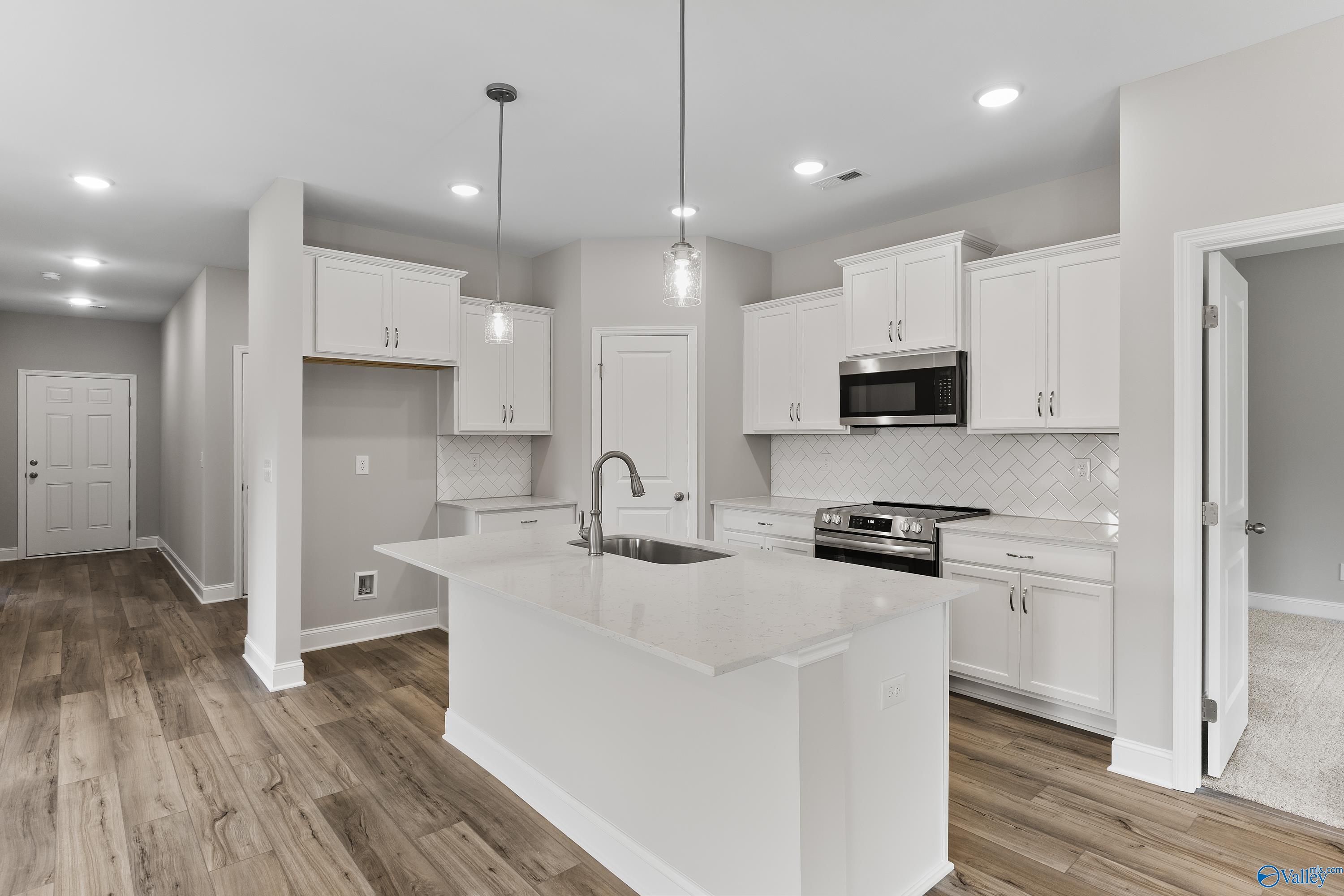 Modern white kitchen with large center island, stainless steel appliances, subway tile backsplash in The Franklin home, Huntsville AL