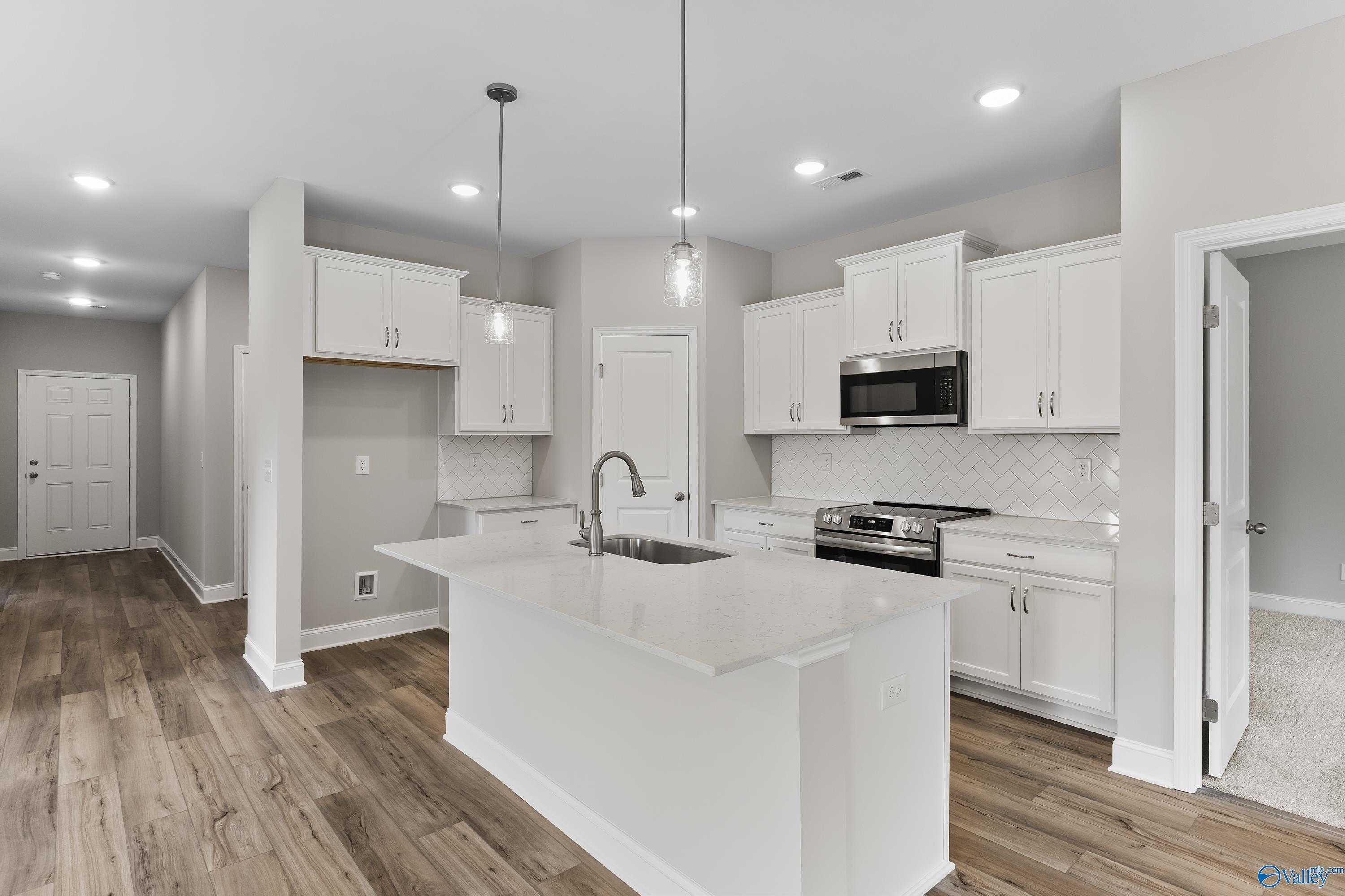Modern white kitchen with large center island, stainless steel appliances, subway tile backsplash in The Franklin home, Huntsville AL