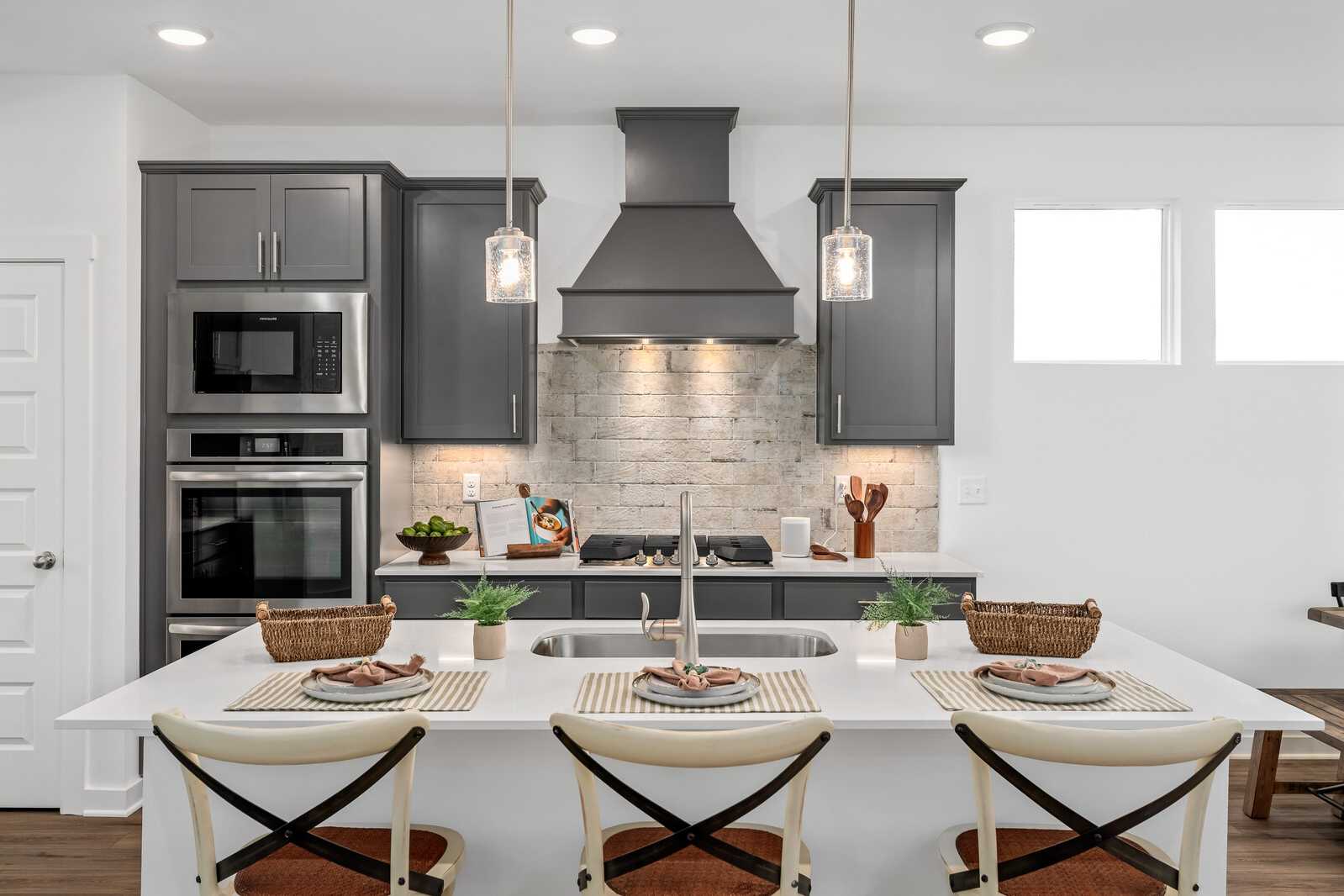 Modern kitchen in Calista Farms White House TN with gray shaker cabinets, stainless steel appliances, subway tile backsplash, and white quartz island