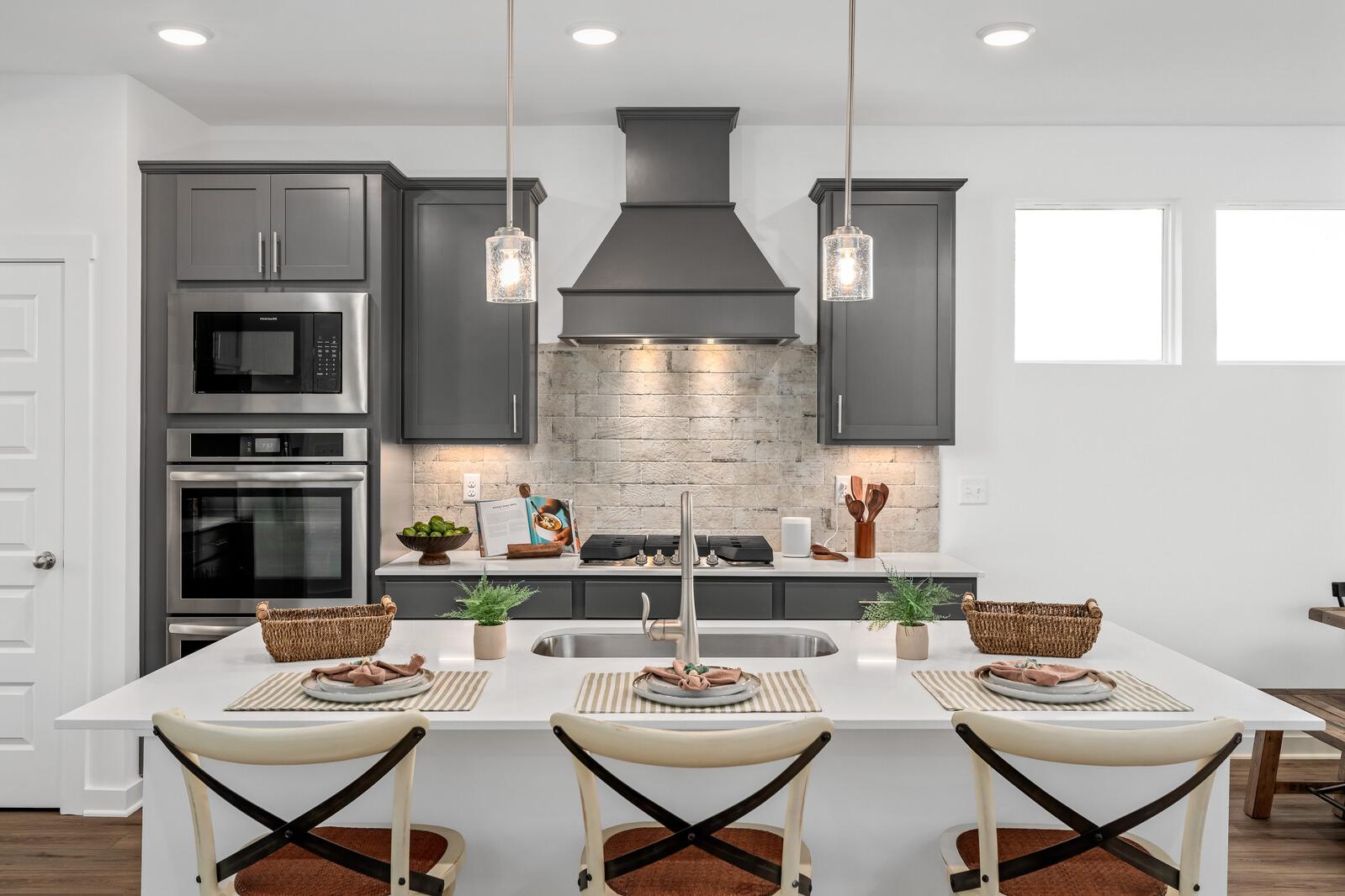 Modern kitchen in Calista Farms White House TN with gray shaker cabinets, stainless steel appliances, subway tile backsplash, and white quartz island
