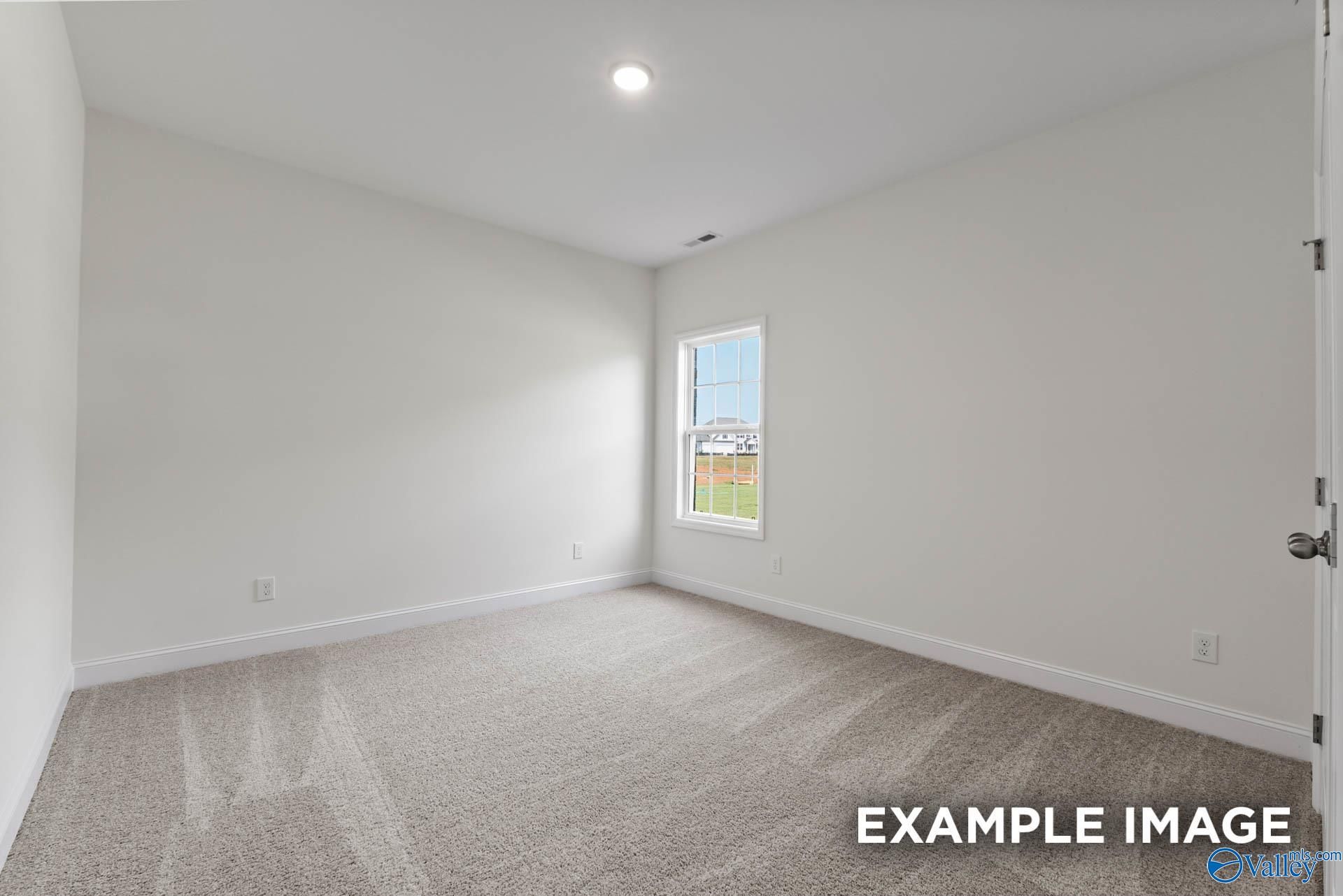 Bright empty secondary bedroom with neutral walls, berber carpet, and window in Davidson Homes The Harrison C, Athens AL