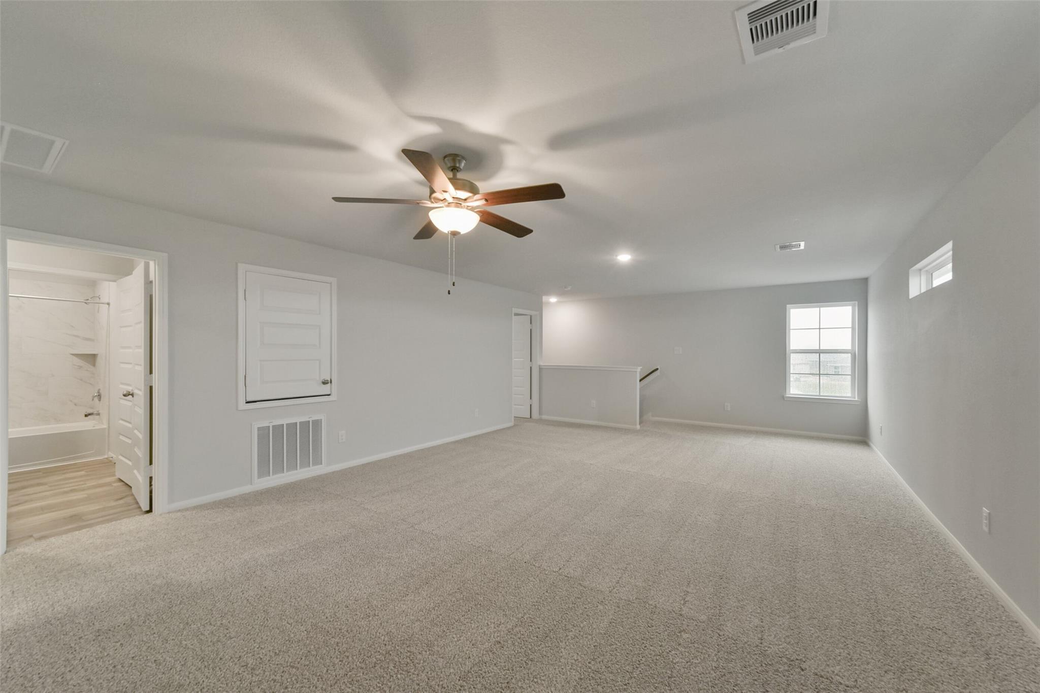 Spacious upstairs bonus room with ceiling fan, carpeted floors, and adjacent bathroom in Davidson Homes San Marcos E, Beasley, Texas