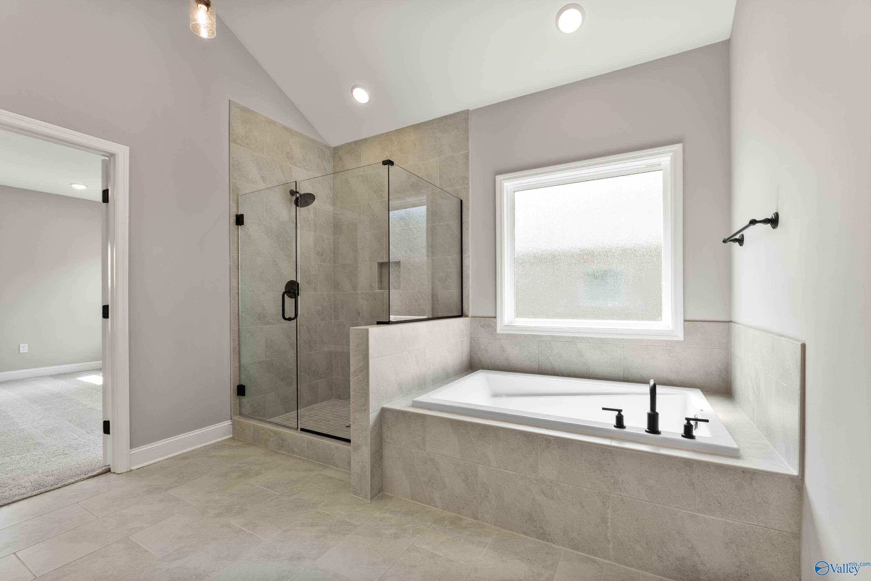 Modern master bath with frameless glass shower, freestanding soaking tub, and large window in Davidson Homes The Finleigh, Toney, Alabama