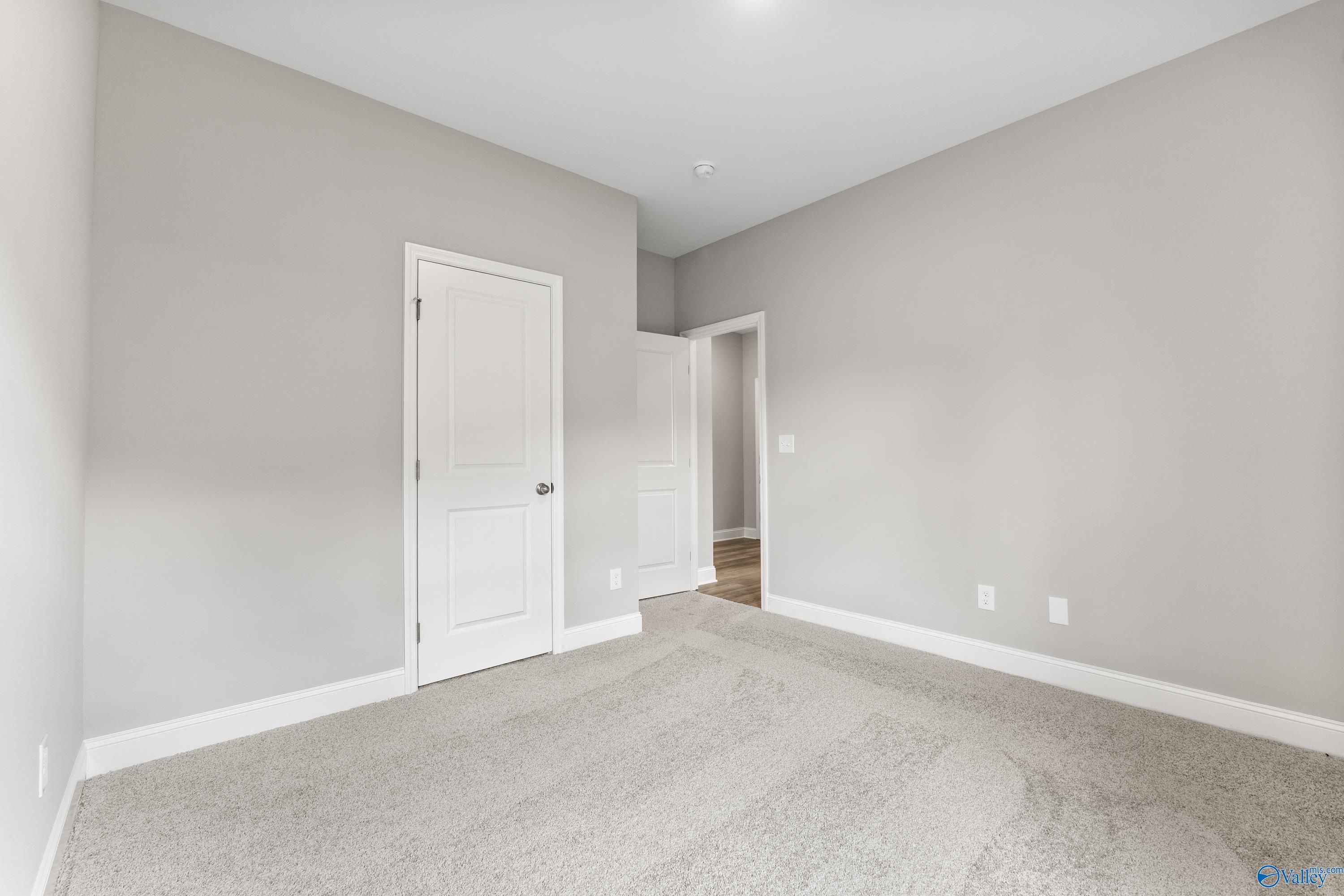 Spacious empty bedroom with gray walls, white doors, and carpet in The Franklin C 3-bedroom home, Huntsville, AL