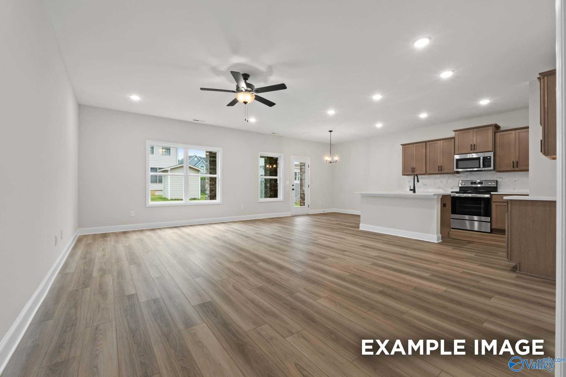 Spacious open-concept kitchen and living area with hardwood floors, ceiling fan, and stainless appliances in The Camden D, Huntsville, AL
