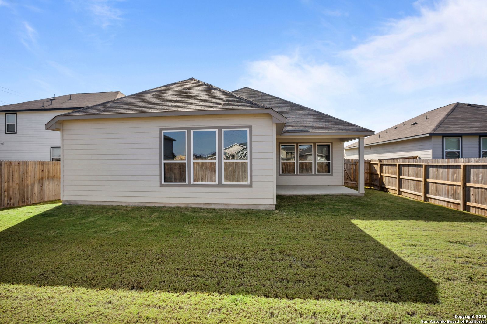 Back view of Davidson Homes The Collin B: single-story 3-bedroom with covered patio, large windows, and fenced grassy yard in Hannah Heights, Seguin, Texas