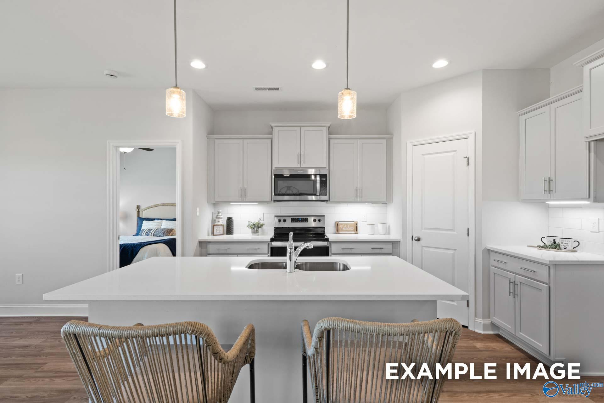 Modern kitchen with white island, gray cabinets, and stainless appliances in The Franklin floor plan, Blue Spring, Alabama.