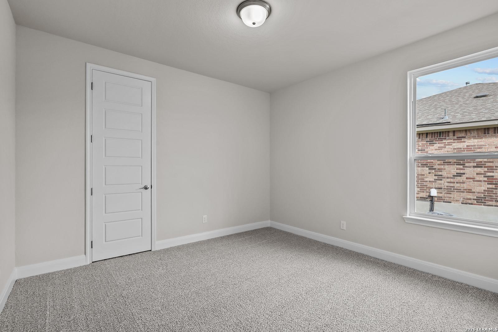 Spacious secondary bedroom with neutral carpet in The Lanier H floor plan by Davidson Homes in Ladera, San Antonio, Texas.