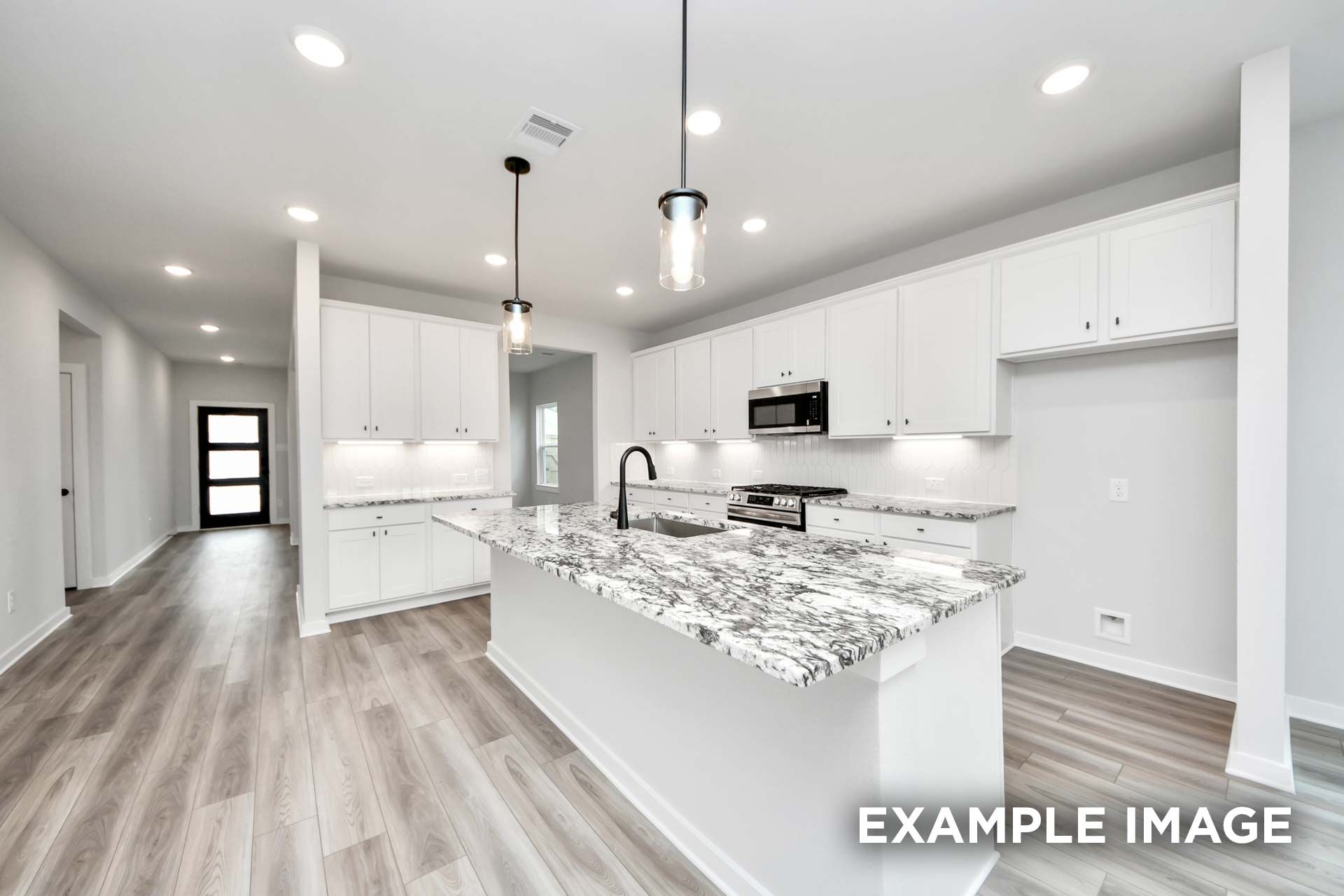 Modern kitchen in The Sorrento featuring white cabinetry, granite island, and wood-style flooring in Crosby, Texas.