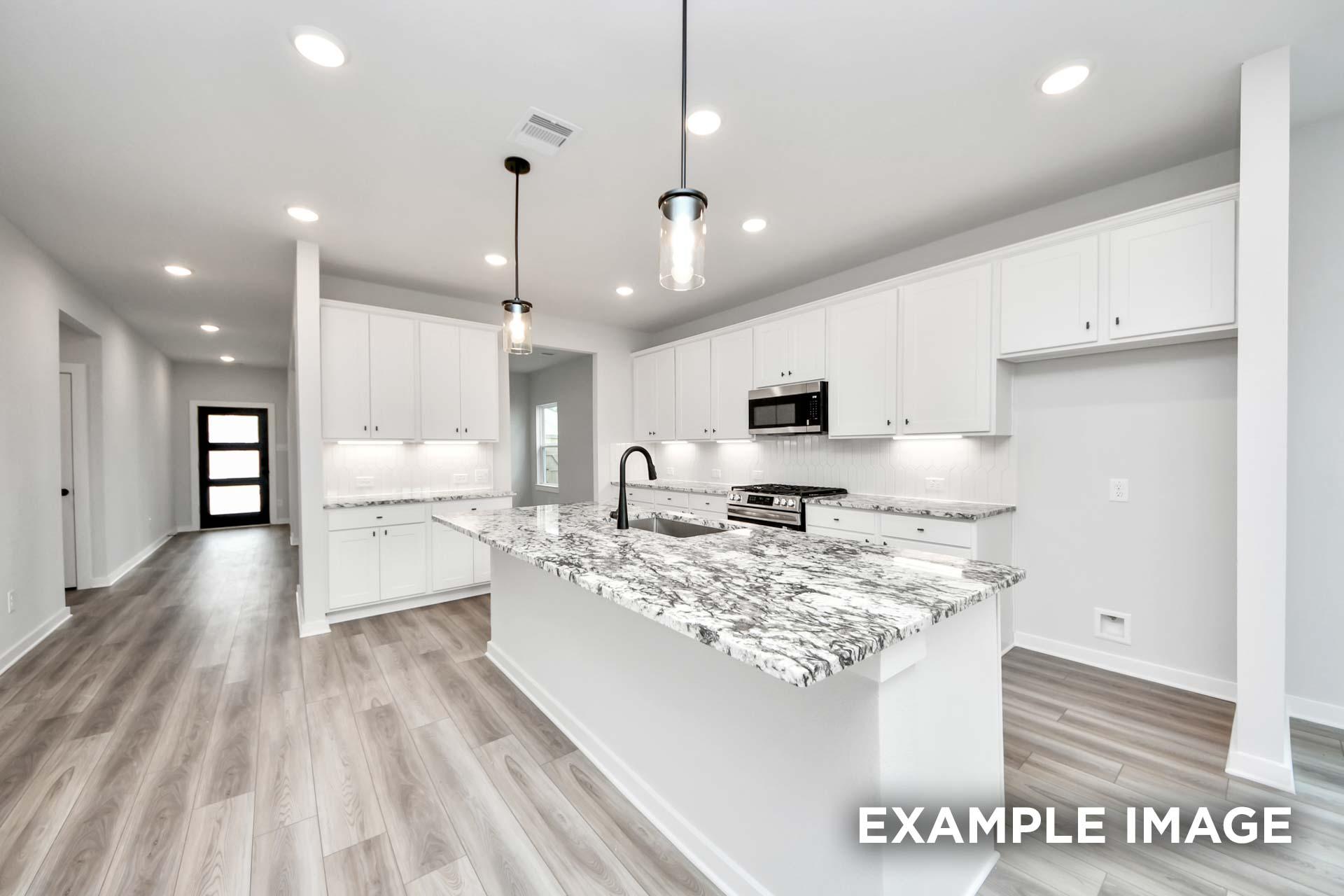 Modern kitchen in The Sorrento featuring white cabinetry, granite island, and wood-style flooring in Crosby, Texas.