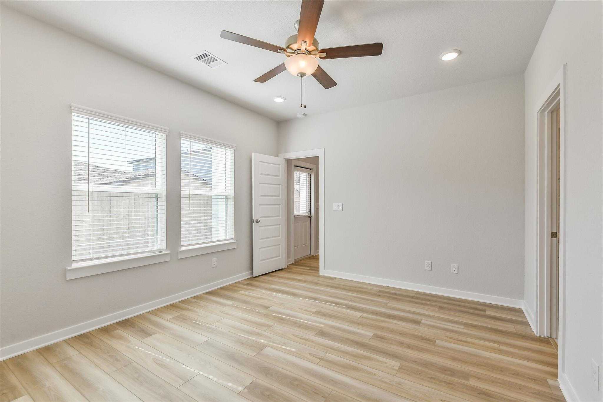 Bright secondary bedroom with ceiling fan, large windows, wood flooring in Davidson Homes The Rio Grande H, Magnolia, Texas
