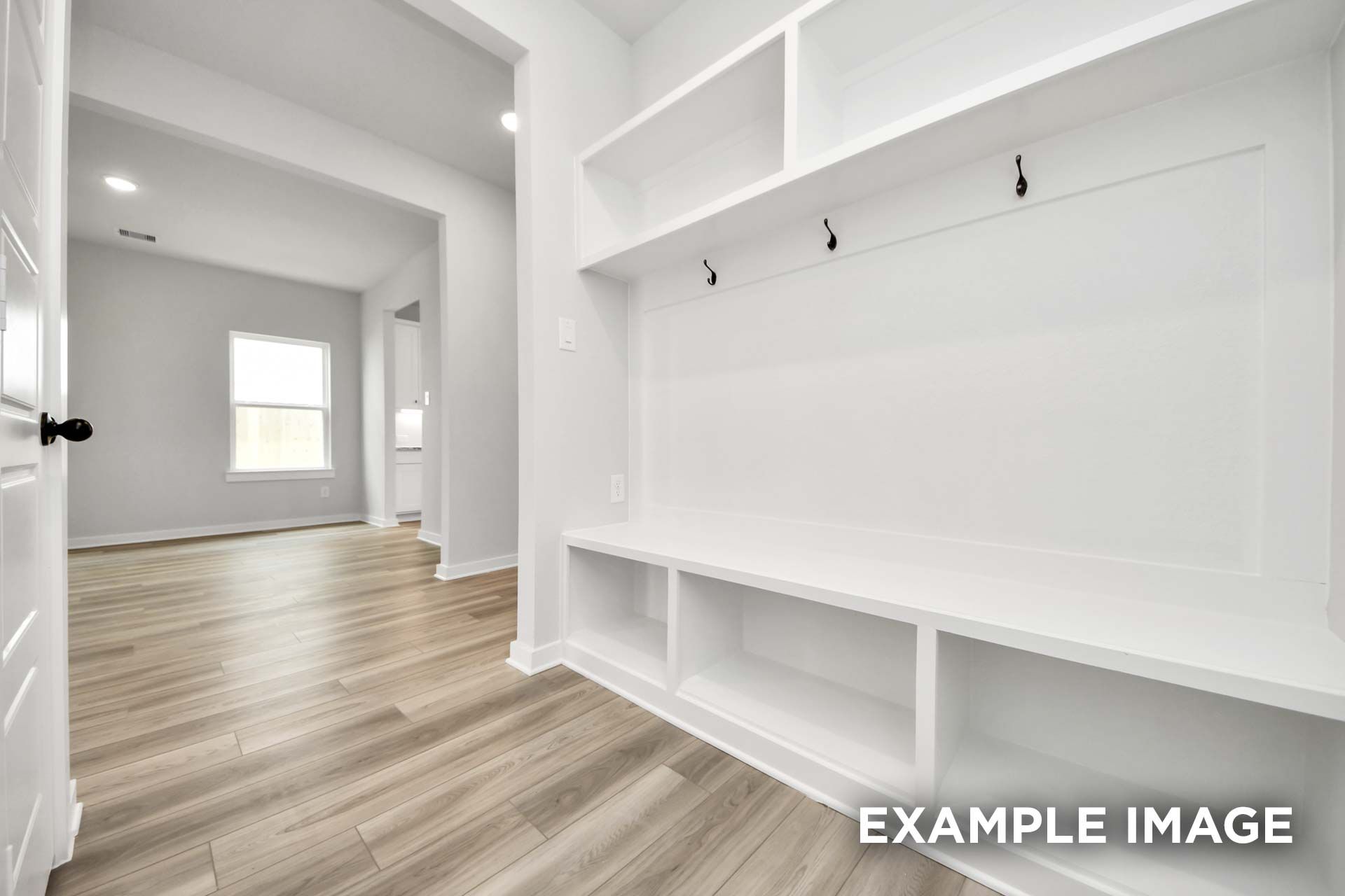 Built-in white mudroom bench with storage and hooks in The Sorrento home design featuring wood-look flooring.