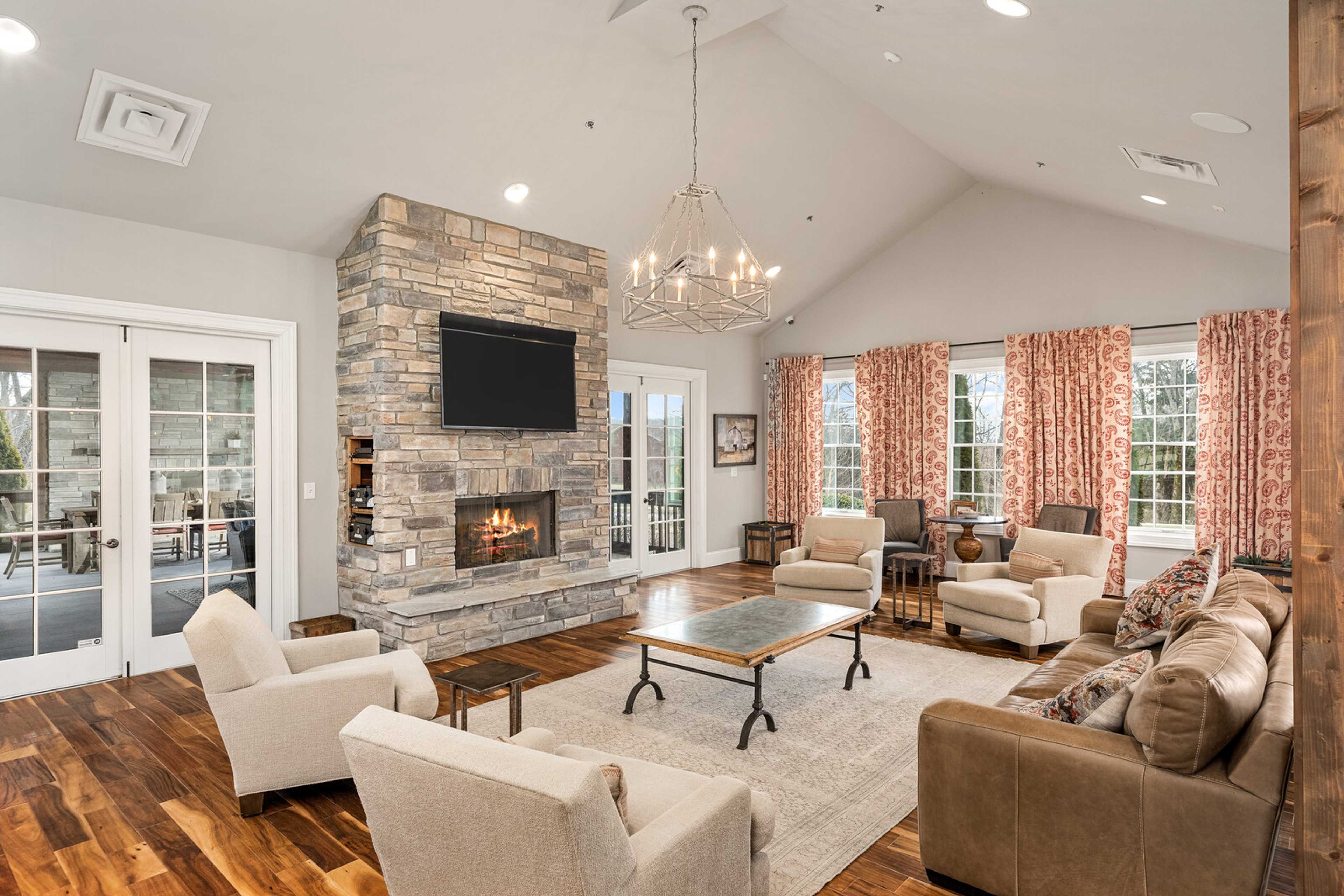 Cozy community lounge at Carellton in Gallatin TN with stone fireplace, leather sofas, chandelier, and French doors to patio