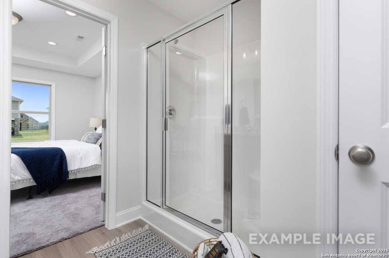 Modern master bathroom with frameless glass shower and adjacent bedroom view in Davidson Homes The Asheville K, Bricewood, San Antonio
