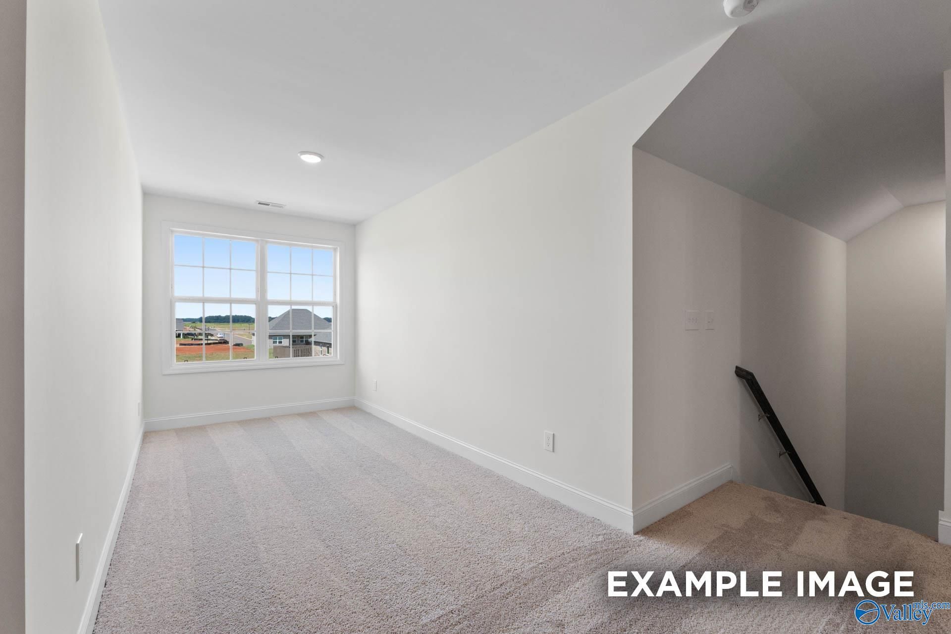 Bright carpeted bonus room upstairs in The Rockford B floor plan at Kendall Downs, Toney, Alabama.