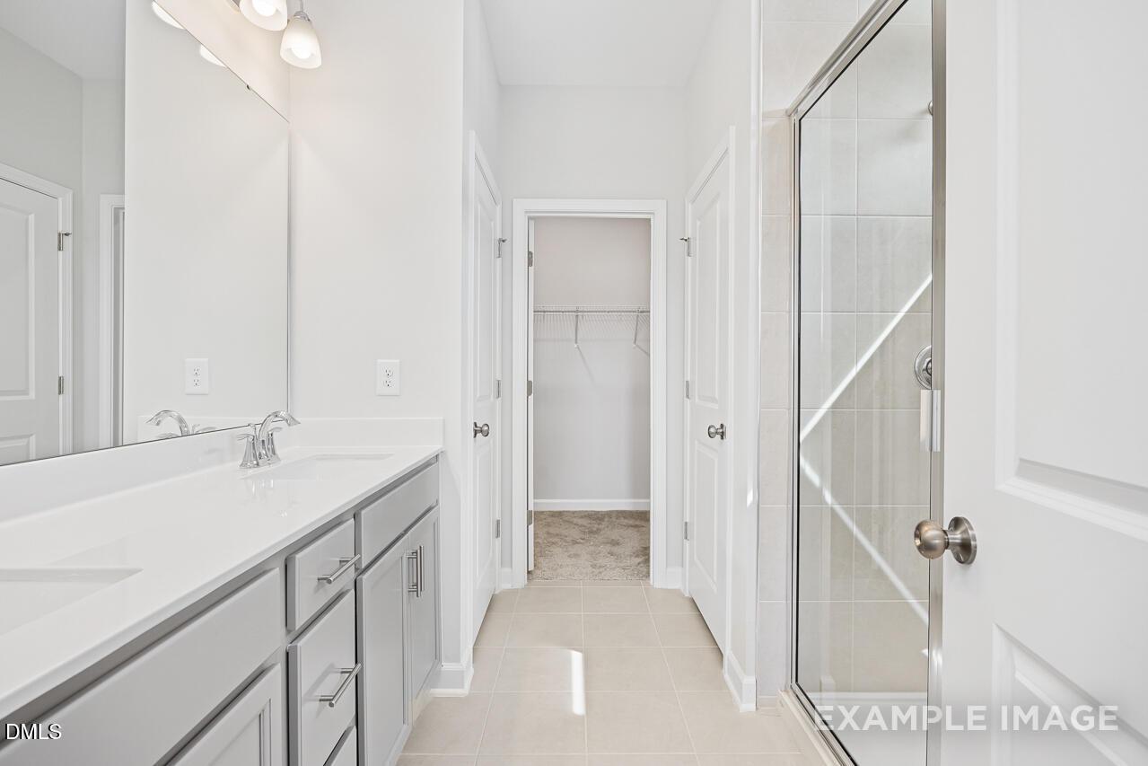 Modern master bathroom with double vanity, walk-in closet, and glass shower in Davidson Homes The Daphne C, Zebulon, NC
