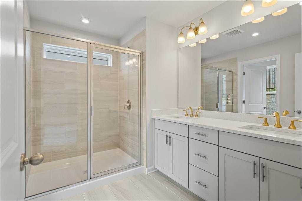 Modern master bathroom with frameless glass shower, double vanity, gold faucets in Davidson Homes The Marion B, Kennesaw, GA