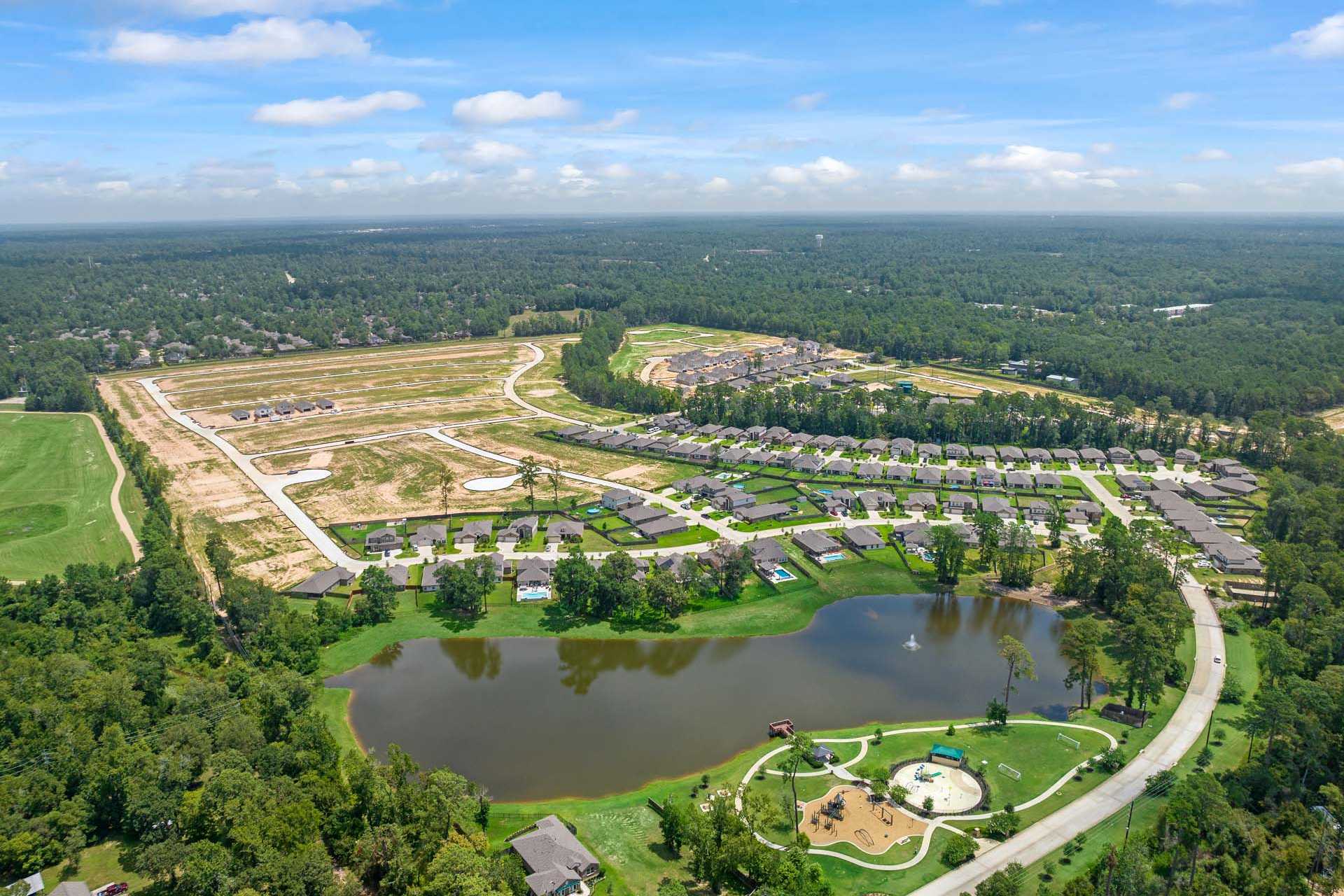 Aerial view of Lakes at Black Oak in Magnolia Texas with central lake playground new homes and wooded surroundings