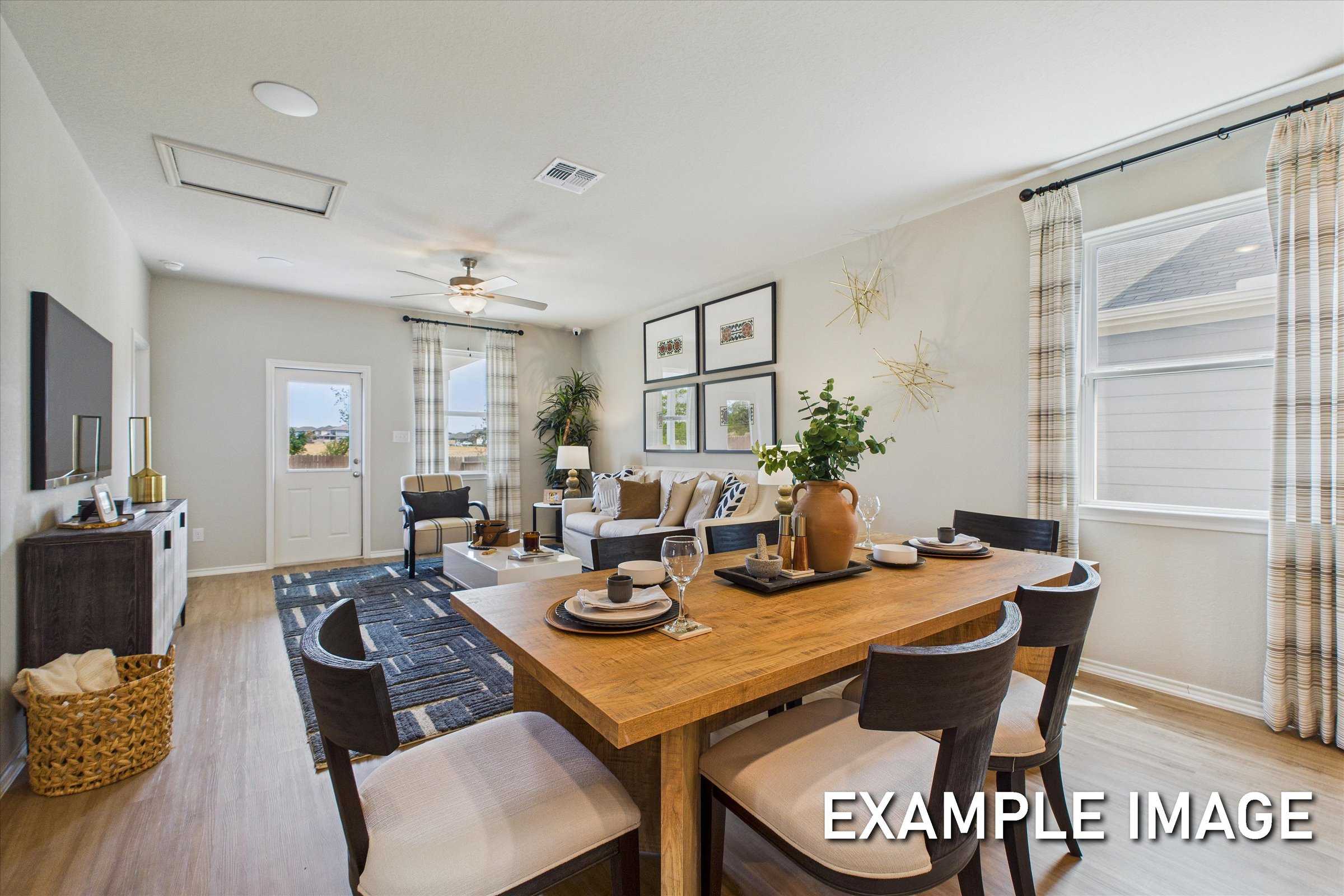 Open-concept living and dining area with hardwood floors, wooden table, TV, and modern decor in Davidson Homes The Sabine C, San Antonio