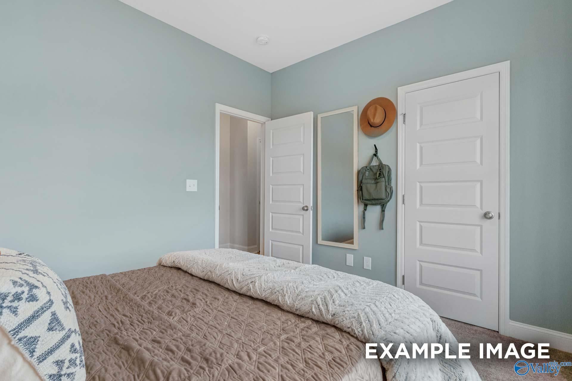 Cozy bedroom with soft blue walls and plush bedding in Davidson Homes The Camilla C floor plan, Hartselle, Alabama