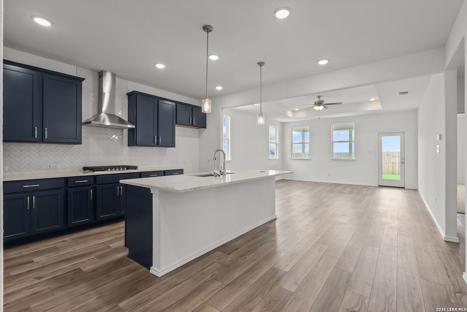 Modern open-concept kitchen with navy cabinets, white quartz island, herringbone backsplash in Davidson Homes The Glenwood E, Elmendorf, Texas