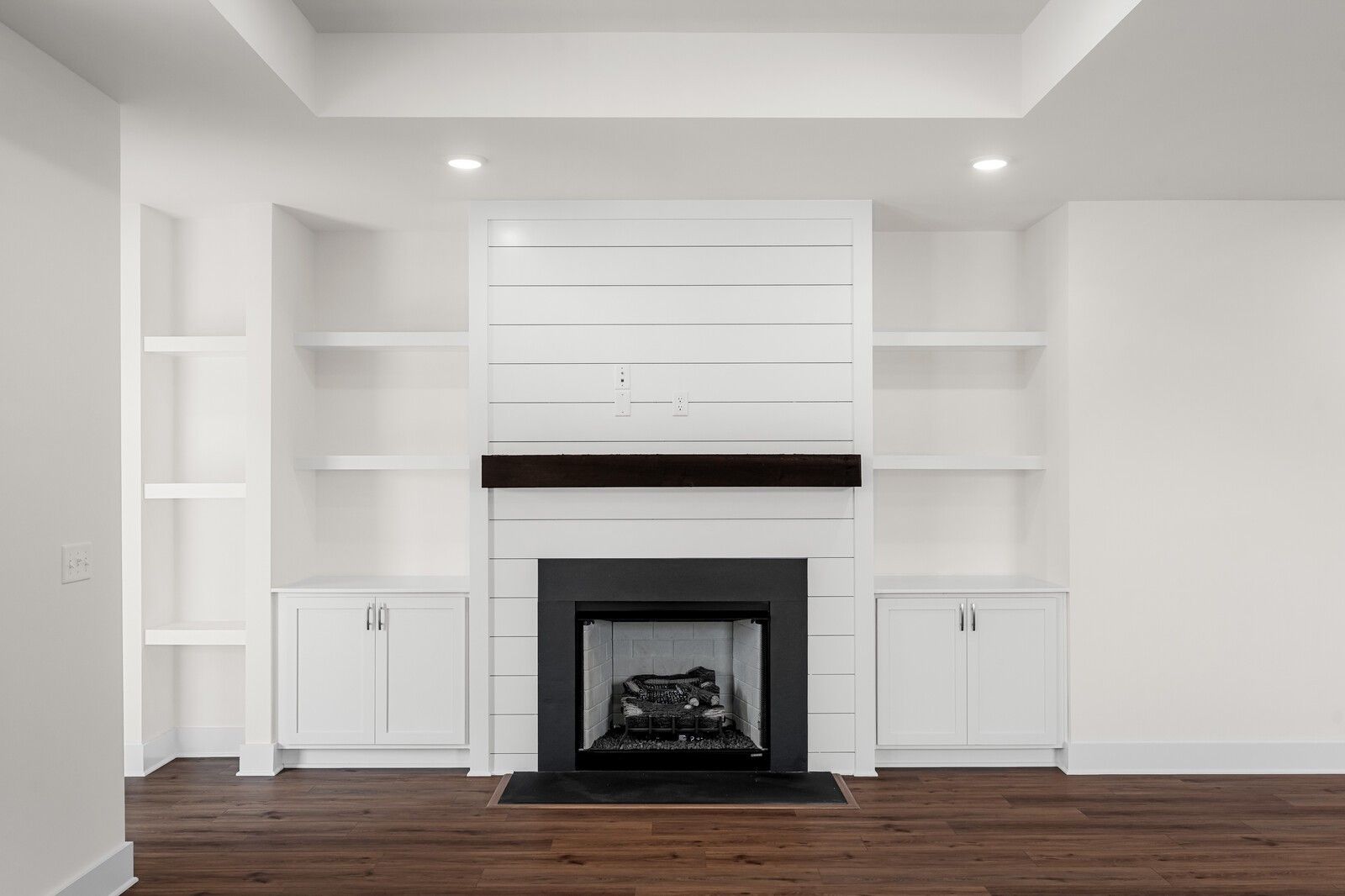 Modern living room fireplace with white shiplap, wood mantel, and built-in shelving in The Prairie C floor plan, Gallatin.