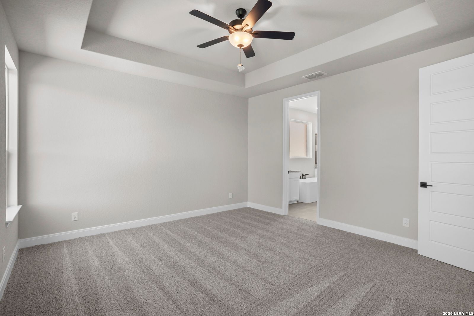Spacious primary bedroom with tray ceiling and en-suite bathroom in Davidson Homes The Jennings G plan, Ladera, San Antonio.