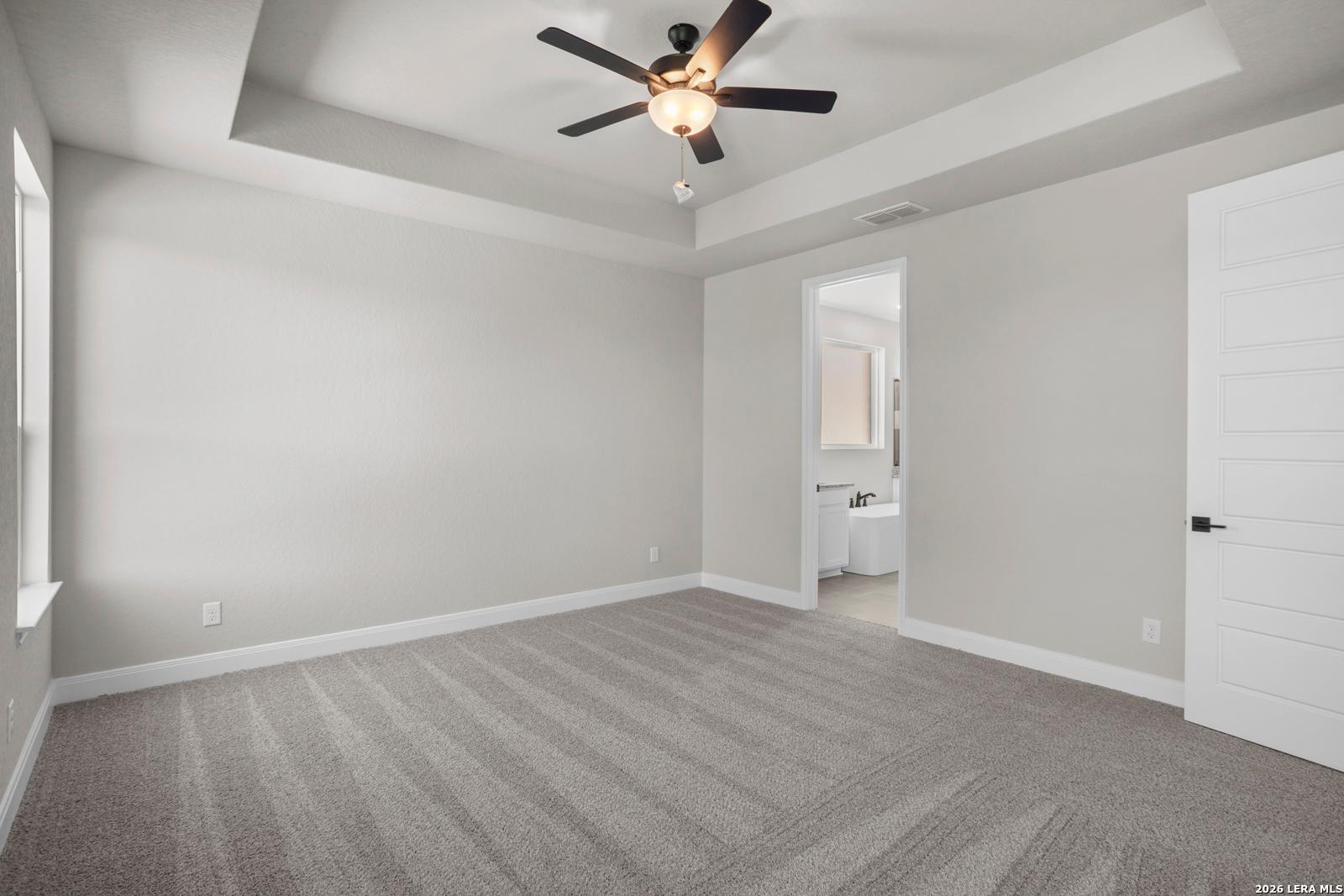 Spacious primary bedroom with tray ceiling and en-suite bathroom in Davidson Homes The Jennings G plan, Ladera, San Antonio.