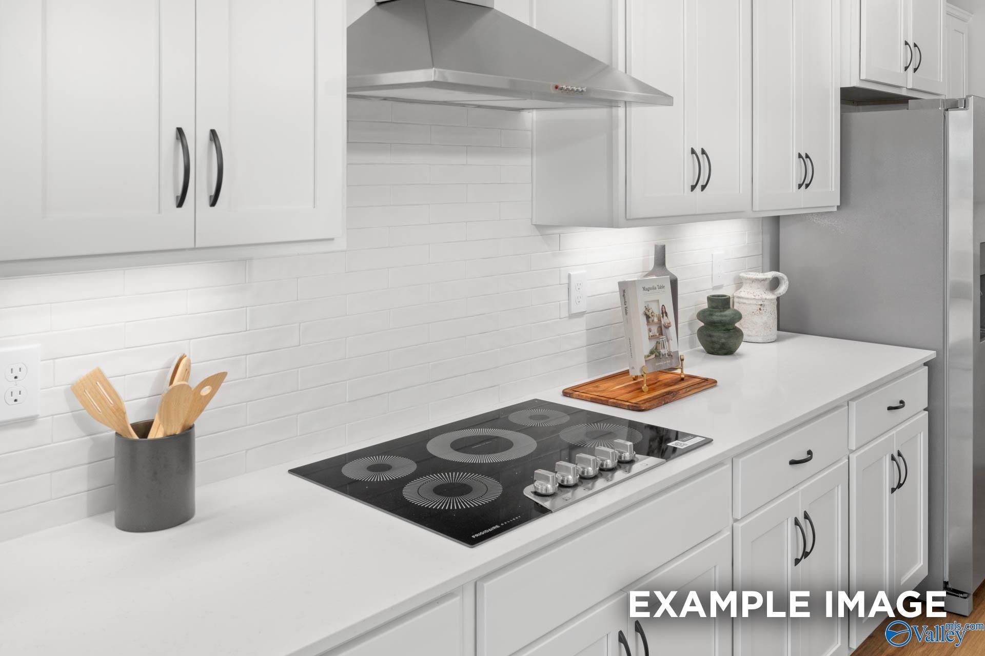 Modern white kitchen featuring gas cooktop, stainless hood, subway tile backsplash in The Finleigh 5-bed home, Decatur AL