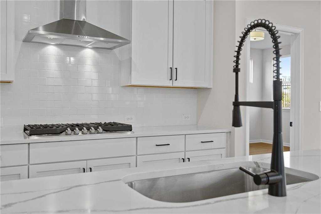 Modern kitchen with white shaker cabinets, quartz counters, subway tile backsplash, and black faucet in Davidson Homes The Edison A, Loganville, GA