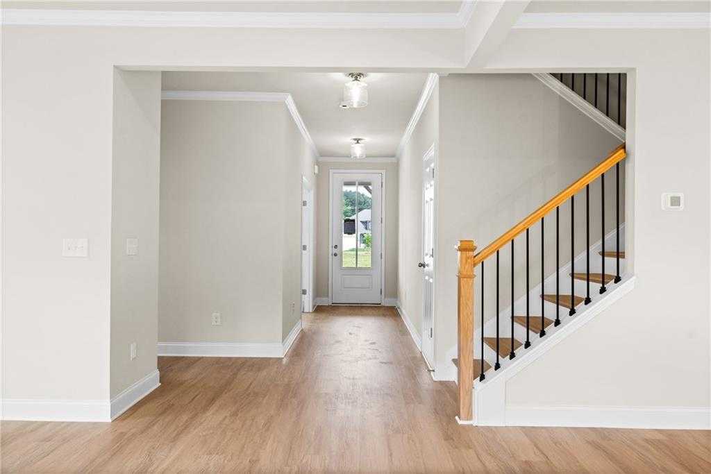 Bright entry foyer with hardwood floors, wooden staircase, and glass door in Davidson Homes The Hickory B at Wehunt Meadows, Hoschton, Georgia