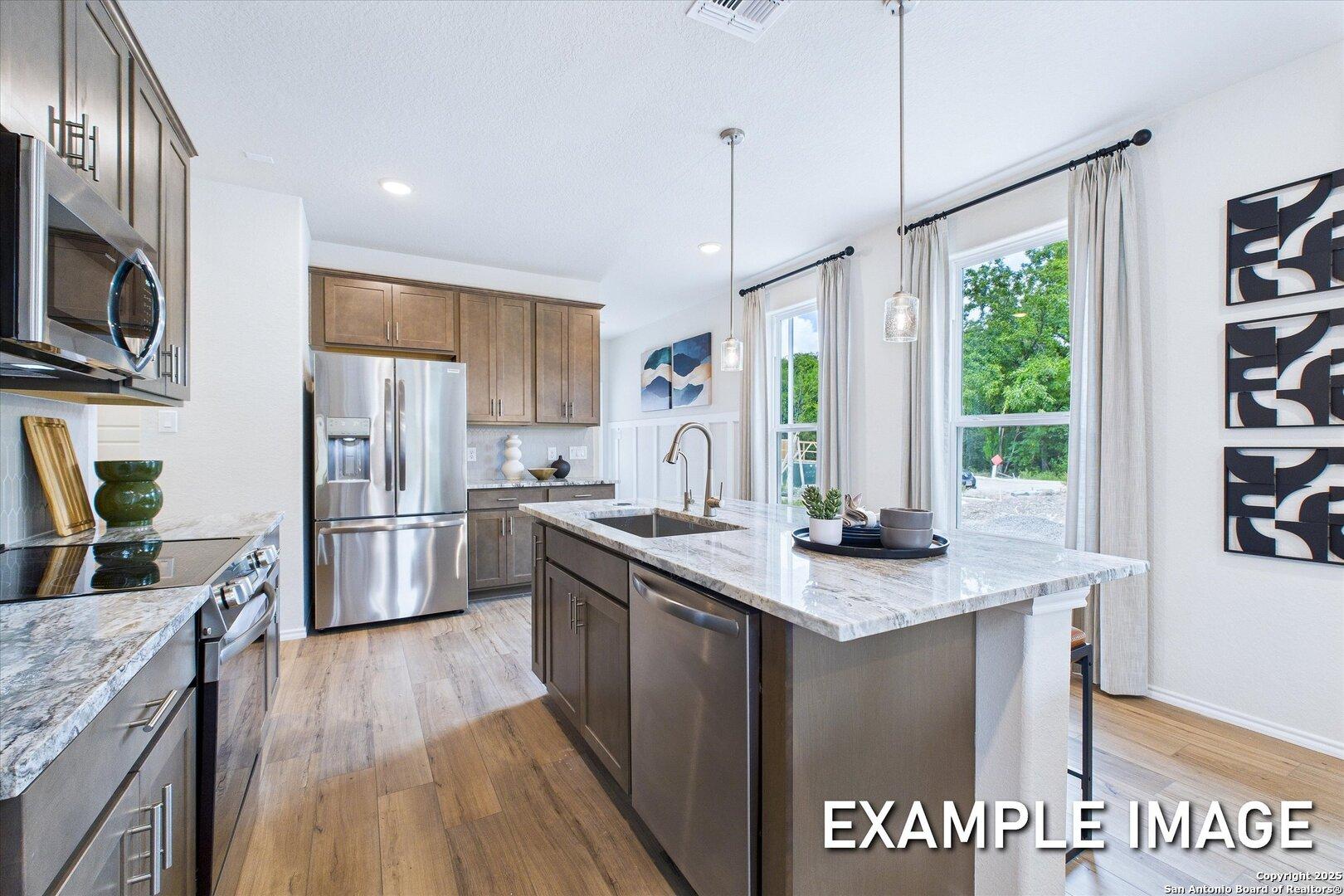 Modern kitchen with quartz island, stainless steel appliances, shaker cabinets, and large windows in Davidson Homes The Gillian C, San Antonio