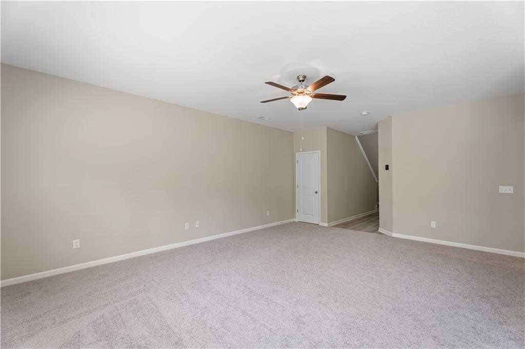 Spacious empty bedroom with beige carpet, ceiling fan, and neutral walls in Davidson Homes The Bartlett, Phenix City