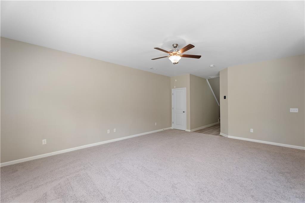 Spacious empty bedroom with beige carpet, ceiling fan, and neutral walls in Davidson Homes The Bartlett, Phenix City