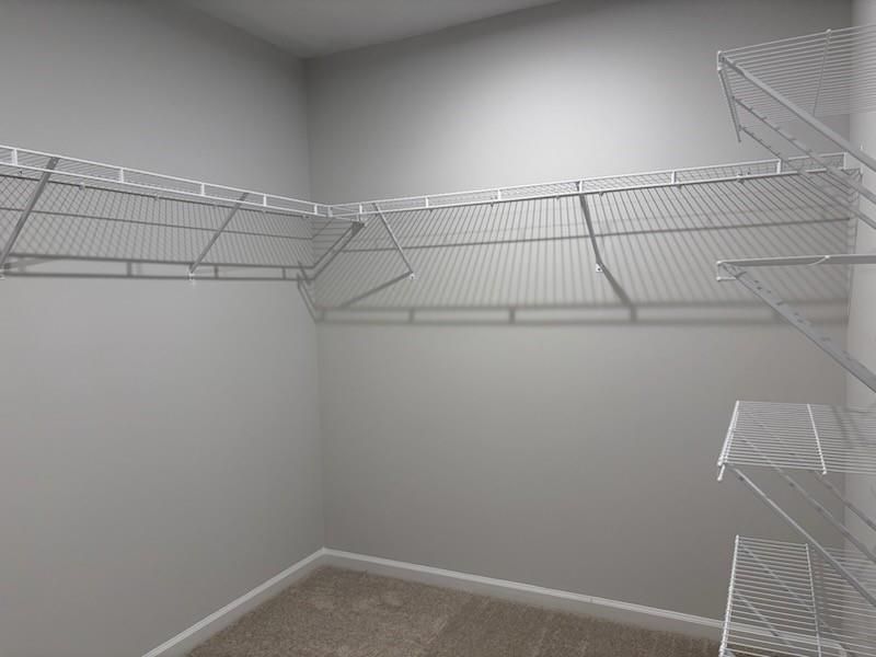 Spacious walk-in closet with white wire shelving on gray walls in Davidson Homes Cary A, Lake Shore, Winder, Georgia