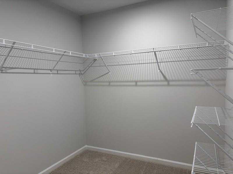 Spacious walk-in closet with white wire shelving on gray walls in Davidson Homes Cary A, Lake Shore, Winder, Georgia