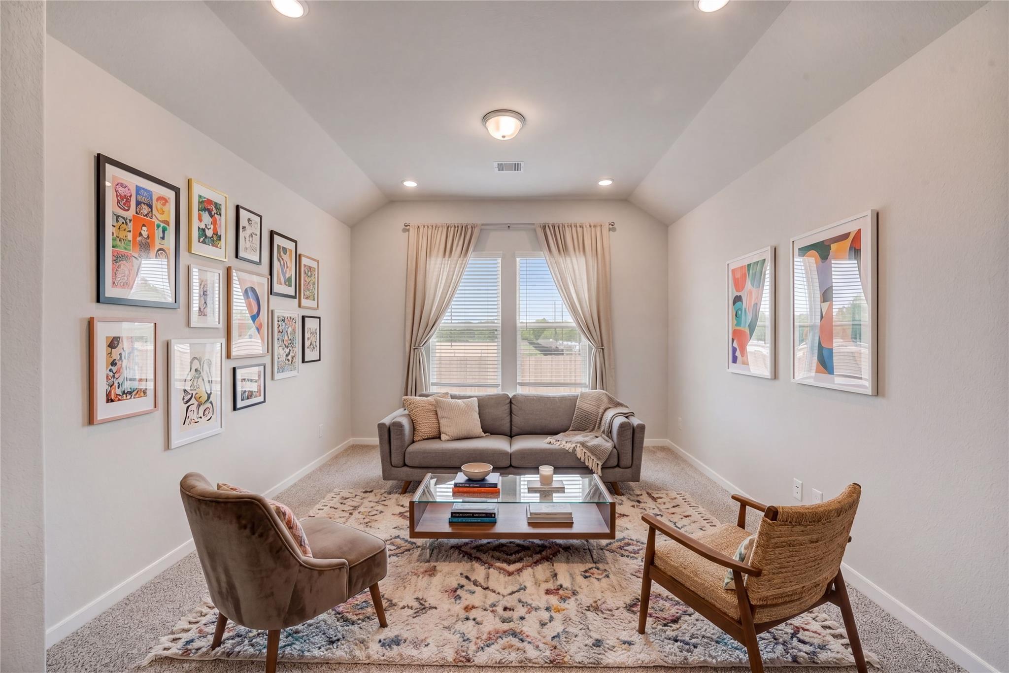 Cozy study with gray sofa, velvet armchair, rattan chair, art gallery wall, large windows in Davidson Homes Acadia C, Magnolia TX