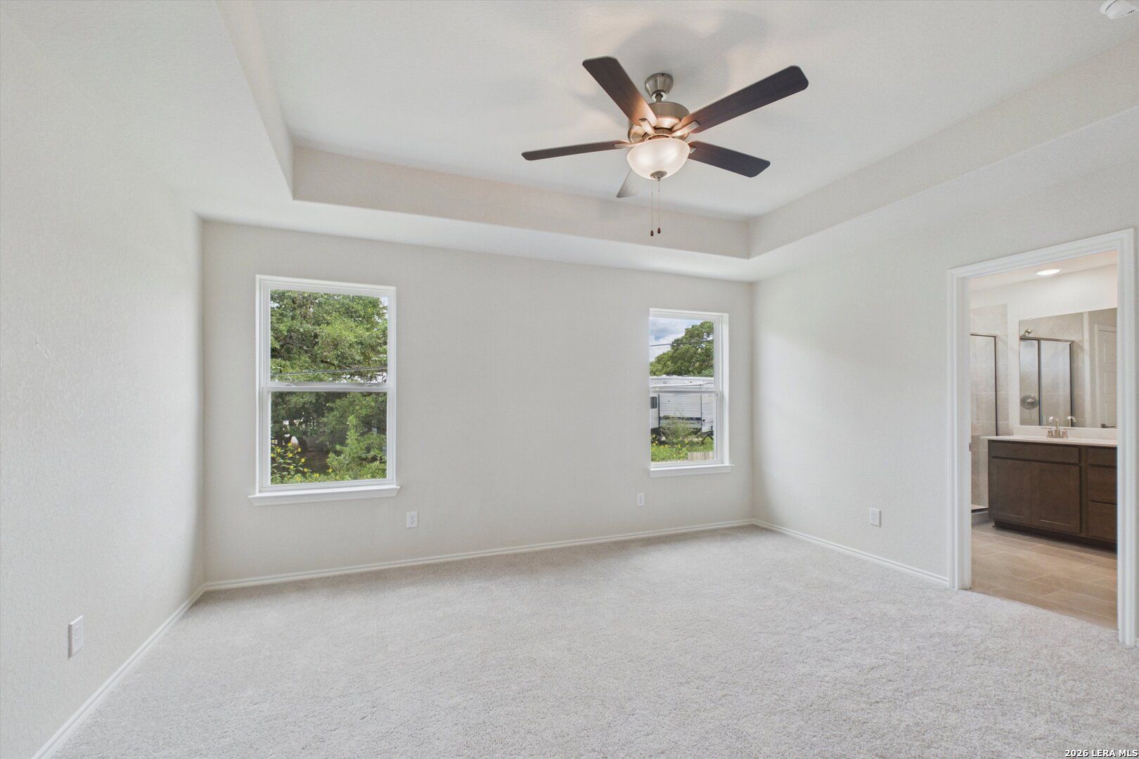 Bright primary bedroom with tray ceiling and en-suite bathroom in Davidson Homes The Charlotte B, San Antonio, Texas.