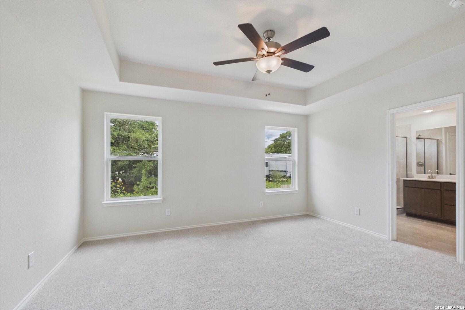 Bright primary bedroom with tray ceiling and en-suite bathroom in Davidson Homes The Charlotte B, San Antonio, Texas.