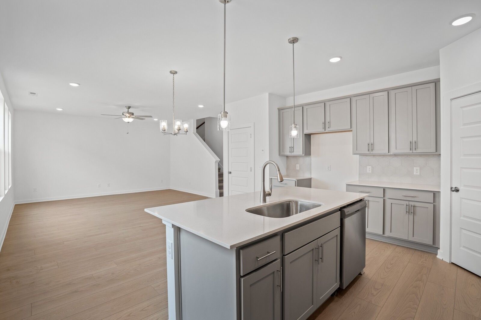 Modern open-concept kitchen with white quartz island, gray cabinets, and pendant lights in The Logan C, Davidson Homes, Calista Farms, White House, TN