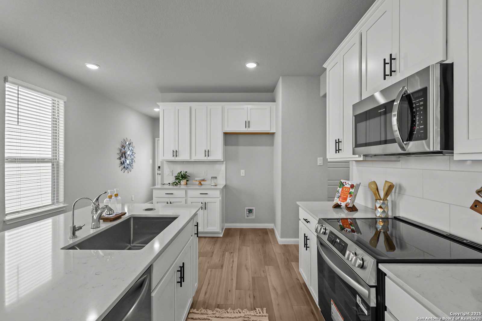 Modern white kitchen with quartz countertops, stainless appliances, island sink in Davidson Homes The Gillian C, San Antonio TX