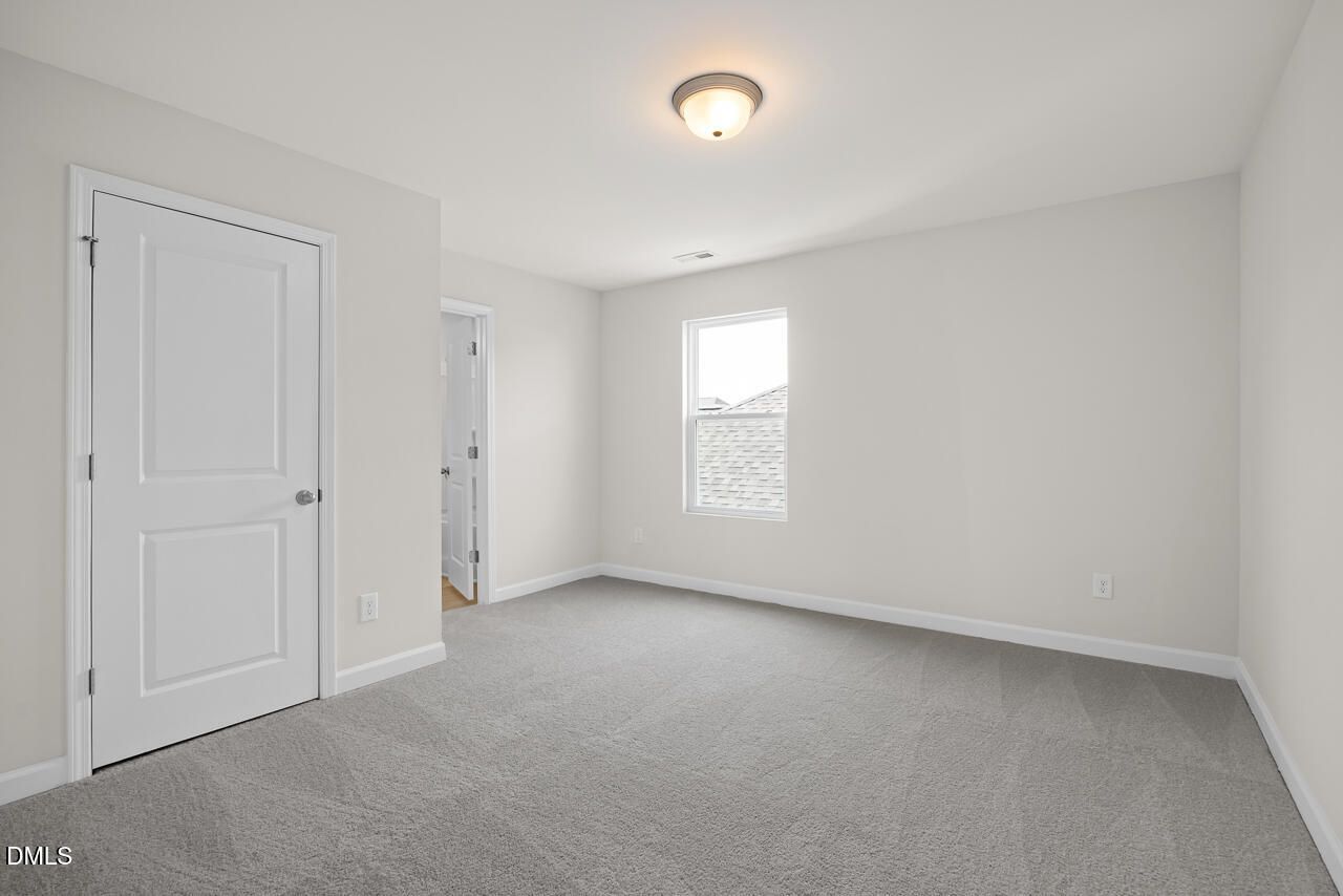 Bright, carpeted bedroom with neutral walls in The Gavin A floor plan at Gregory Village, Lillington, North Carolina.