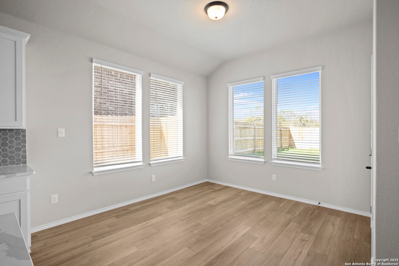 Bright room with light gray walls, large windows overlooking fenced backyard, hardwood floors, built-in cabinets in Davidson Homes The Sequoia A, Converse, Texas