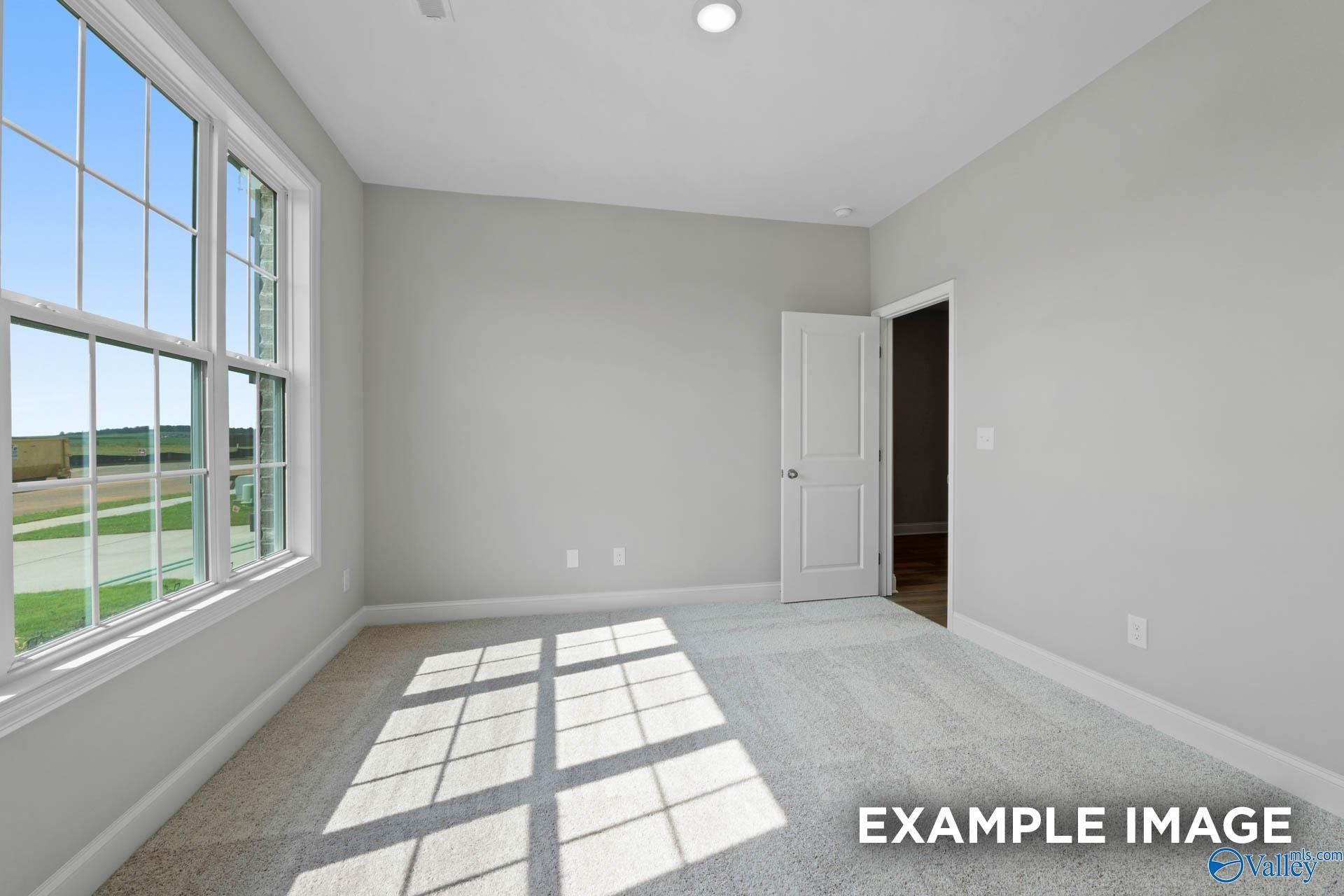 Bright bedroom with large windows, natural light, and gray walls in Davidson Homes The Montgomery B, Hartselle, Alabama